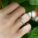 Diamond heart ring worn on hand, shown against green leaves