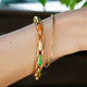 Chunky enamel-accented gold bracelet worn on model’s wrist