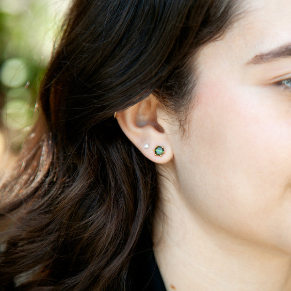 Green tourmaline hexagon stud earrings in 14kt yellow gold displayed on model’s ear