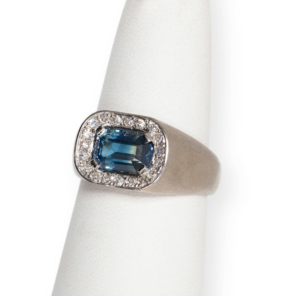 Horizontal view of 18kt white gold sapphire and diamond ring featuring emerald-cut blue sapphire and diamond halo