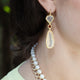 Woman wearing long 18kt yellow gold drop earrings with Mexican opals and citrine accent stones