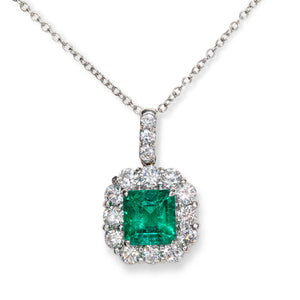 Platinum pendant with vivid Colombian emerald surrounded by diamond halo and diamond-accented bale
