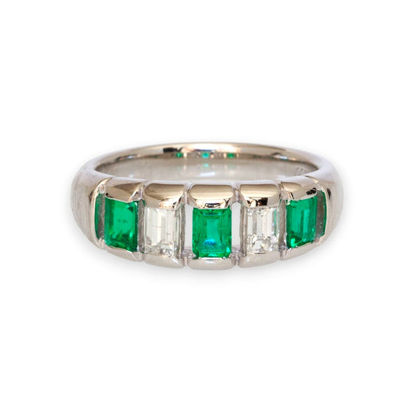 Platinum five-stone ring with emerald-cut emeralds and diamonds on white background