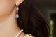 Woman wearing platinum Mexican opal and diamond drop earrings
