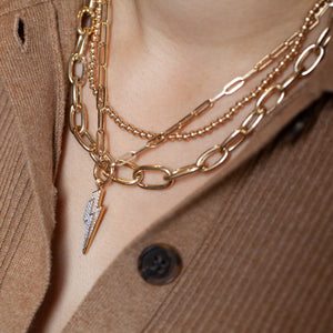 14kt gold beaded necklace layered with other gold chains on model's neck