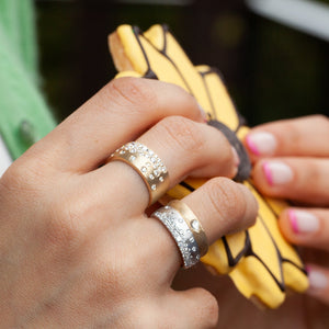 Model hand wearing 14kt white gold scatter band alongside gold scatter ring