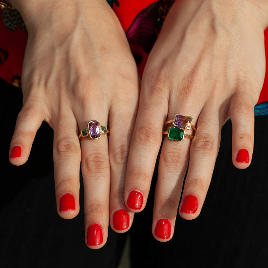 Emerald ring worn on hand, stacked with additional gemstone rings