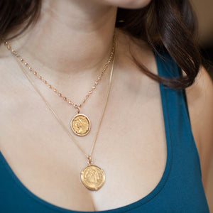 Model wearing 18kt yellow gold pink sapphire necklace layered with coin pendants