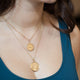 Model wearing 18kt yellow gold pink sapphire necklace layered with coin pendants