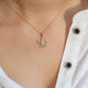 Diamond fleur-de-lis pendant necklace in rose gold on model’s neck